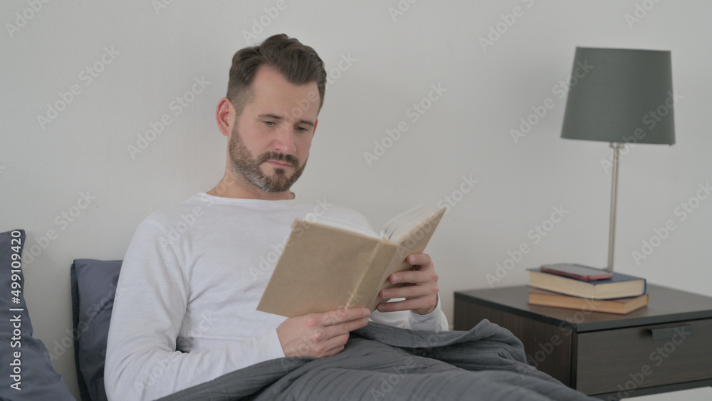 Man Reading Book while Sitting in Bed Man Reading Book while Sitting in Bed