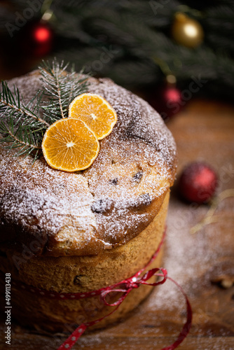 Rustic homemade Christmas traditional Italian holiday panettone cake with festive ribbon, decoration and lights