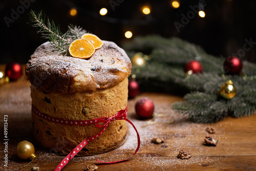 Rustic homemade Christmas traditional Italian holiday panettone cake with festive ribbon, decoration and lights