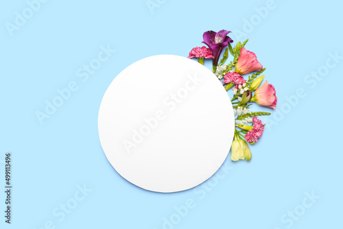 Composition with blank card and flowers on blue background