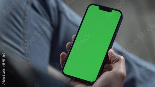 Man Using Smartphone in Vertical Mode with Green Mock-up Screen. Internet Social Networks Browsing News, Financial Reports