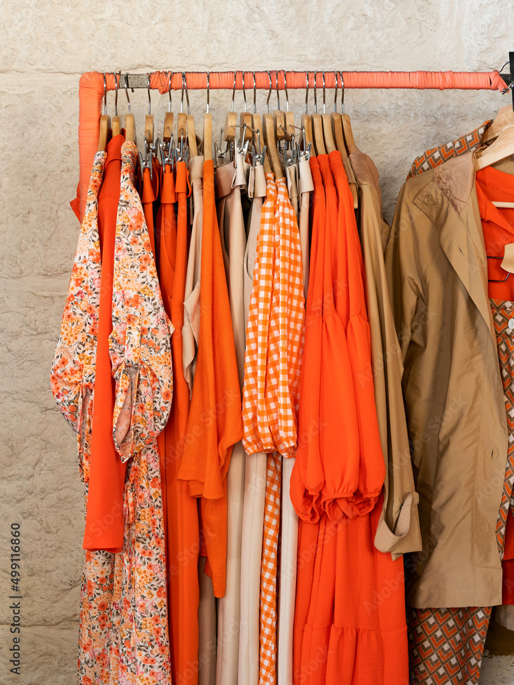 Ropa tonos naranja en perchero de tienda de ropa