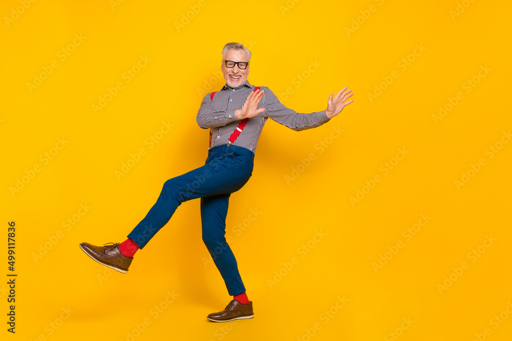Full size photo of cheerful mature man feeling young have fun dancing in club isolated on yellow color background