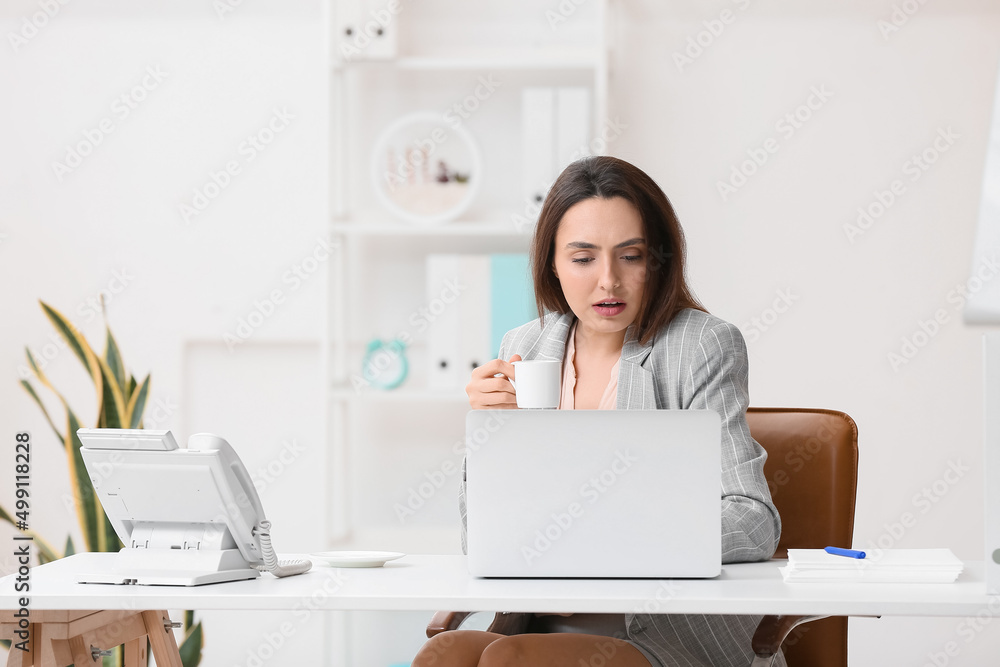 Young secretary drinking coffee while working in office Young secretary drinking coffee while working in office
