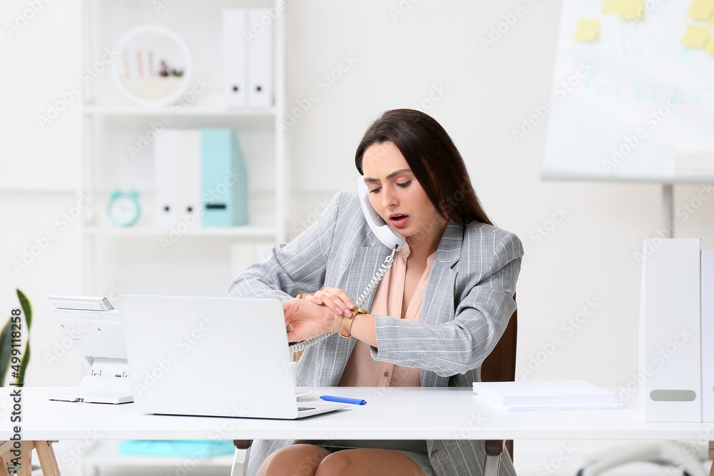Young secretary talking by phone while working in office Young secretary talking by phone while working in office