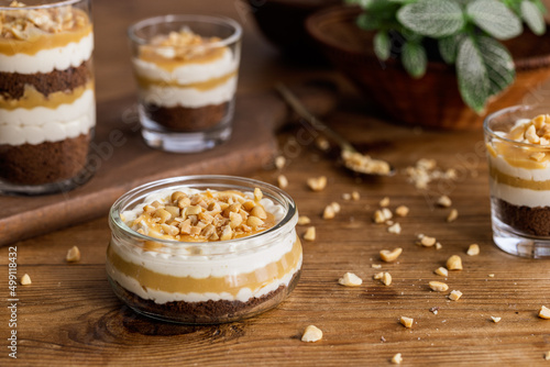 Snickers toffee cream peanut layered dessert in a glass jar on a wooden background