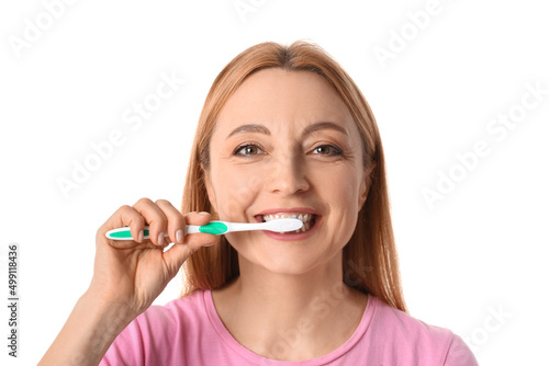 Beautiful mature woman brushing teeth on white background