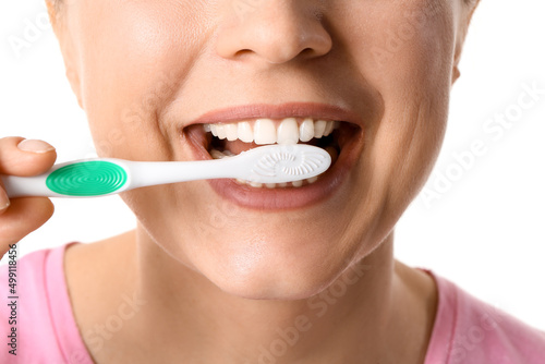 Beautiful mature woman brushing teeth on white background, closeup