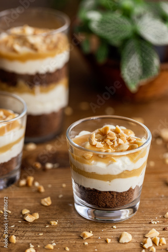 Snickers toffee cream peanut layered dessert in a glass jar on a wooden background