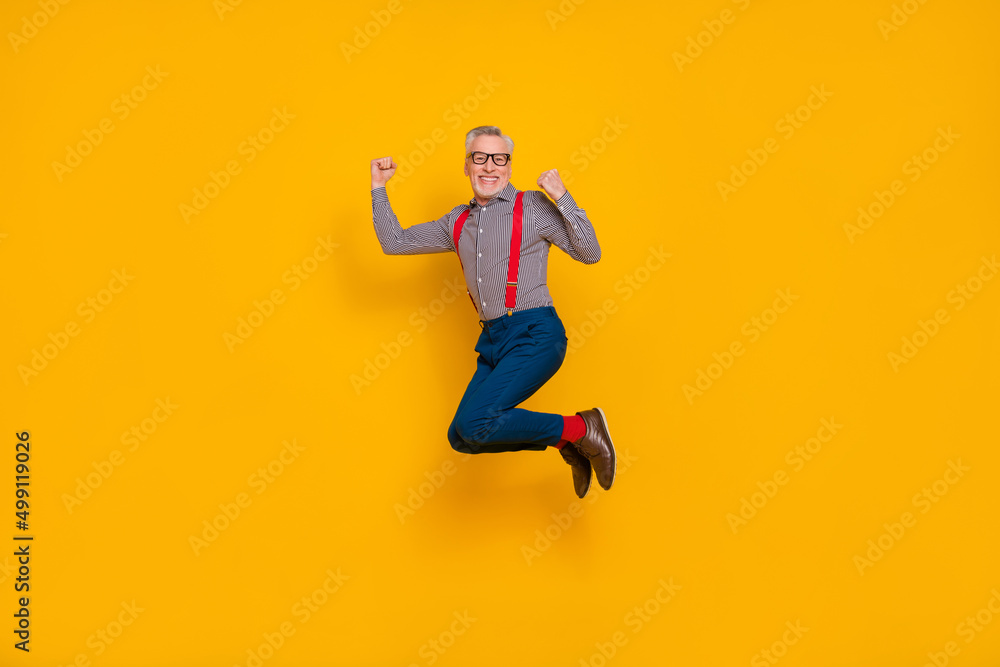 Full body photo of laughing cheerful granddad jumping up in excitement celebrate victory isolated on yellow color background