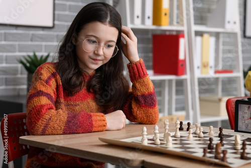 Little girl playing chess d...