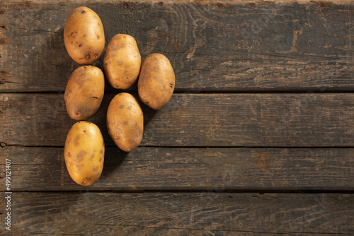 6 yellow potatoes on a wooden texture. Concept: potato, vegetable garden, farming, agriculture