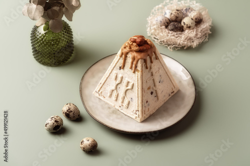 фотографія Traditional Easter cottage cheese dessert Paskha decorated with caramel, nuts, raisins and quail eggs on pastel background