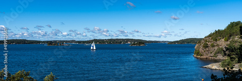 White sailing yacht moving along beautiful forest pine islands. Amazing panorama of blue Baltic sea bay skyline horizon. Rocky shores of Scandinavia at summer day.