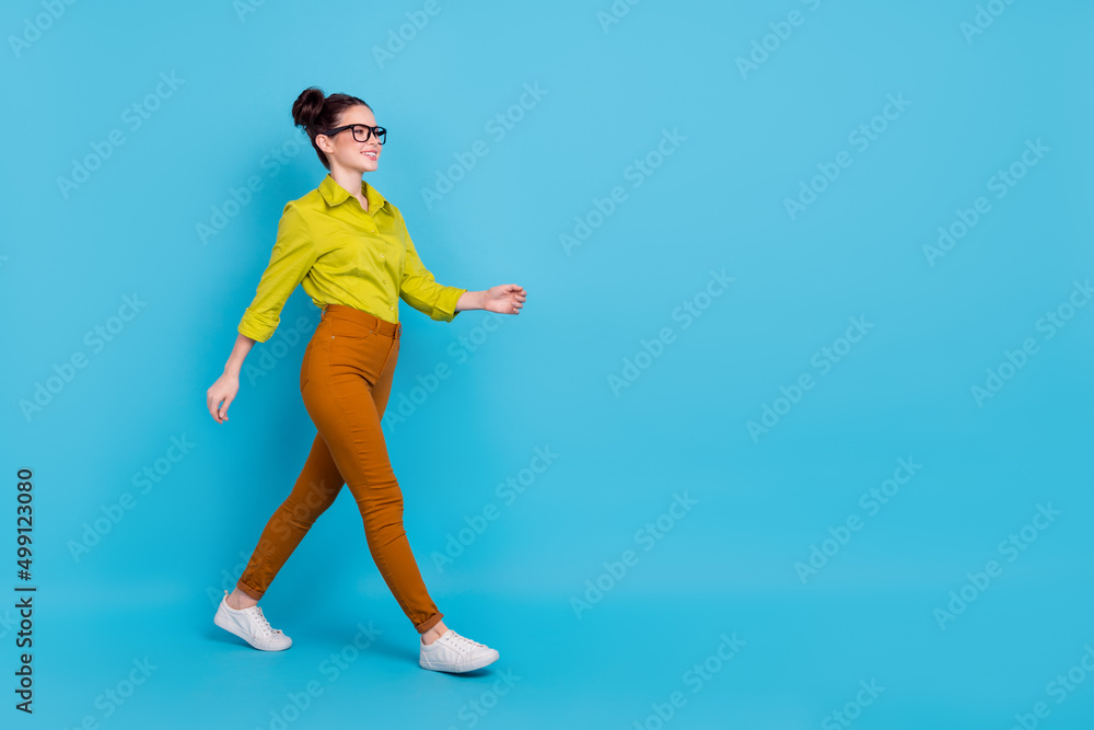Full size profile portrait of satisfied successful lady walk look empty space isolated on blue color background Full size profile portrait of satisfied successful lady walk look empty space isolated on blue color background