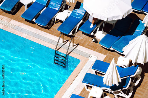 View of a part of a swimming pool and deck chairs in economy hotel Fototapet