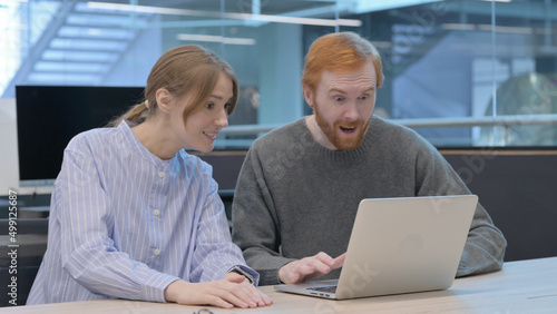 Young Man and Woman Celebrating Success on Laptop 