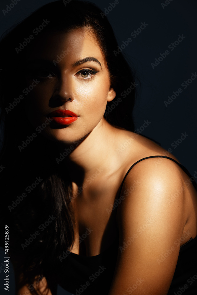 Beauty in the shadows. Studio portrait of an attractive young woman posing against a dark background. Beauty in the shadows. Studio portrait of an attractive young woman posing against a dark background.