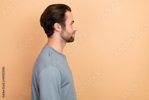 Profile side photo of young man look empty space wear casual clothes isolated over beige color background