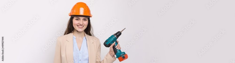 Girl engineer in an orange construction helmet with a screwdriver and a hammer on a white background. Girl engineer in an orange construction helmet with a screwdriver and a hammer on a white background.