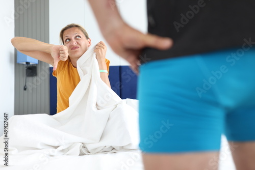 Canvastavla Upset woman holding thumbs down in bedroom with man