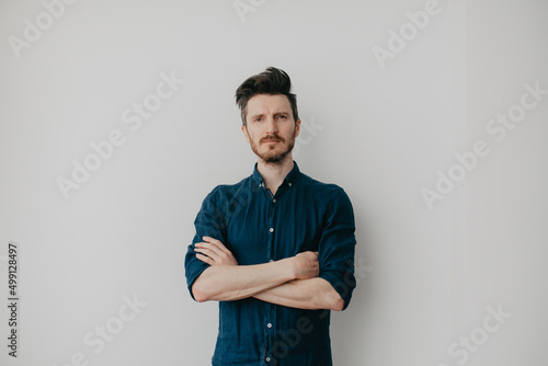Handsome young man in a dark blue shirt by a light wall. Place for text.