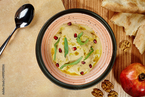 Chicken satsivi in walnut sauce garnished with greens and pomegranate seeds photo