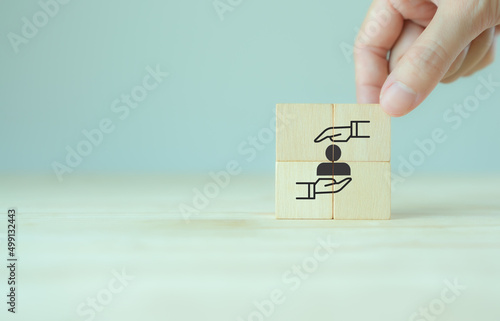 Engagement for customer or employee concept.  Retention, customer loyalty, repurchasing, advocacy. Sustainable business success. Putting wooden cubes with holding person icon on smart background.