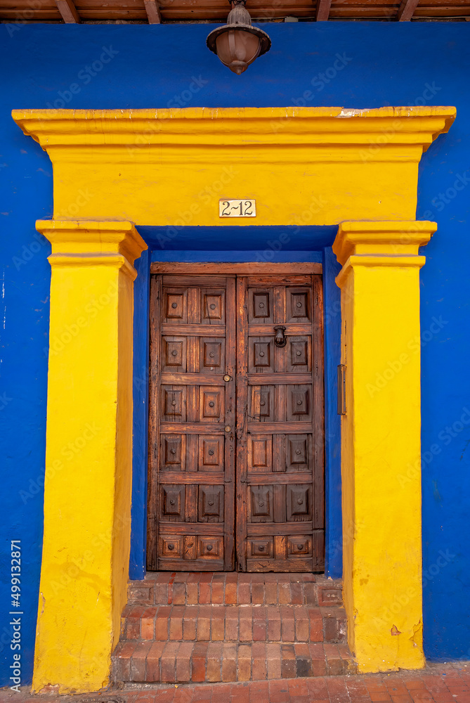 Obraz premium Woodem door in a yellow blue buiding, La Candelaria, Bogotá, Colombia