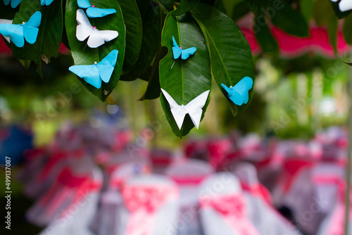 White, blue, paper butterfly perched on a beautiful decorative green leaf.