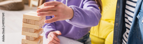 Cropped view of teenager playing wood blocks game near friend at home, banner.