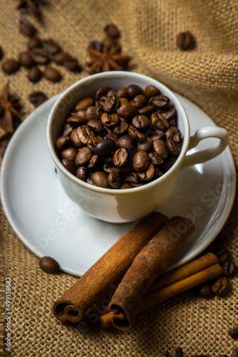 Coffee cup full of coffee beans. Roasted coffee beans on burlap.