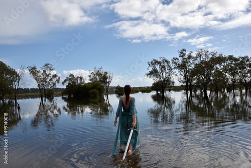 Portrait of beautiful girl wearing flowing fantasy gown in a magical lake background.