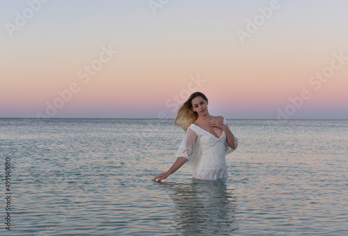 Portrait of beautiful girl wearing flowing fantasy gown in a magical lake background.
