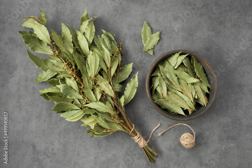 Bowl of dried laurel leaves and bunch of dry green bay leaves, top view, flat lay. photo