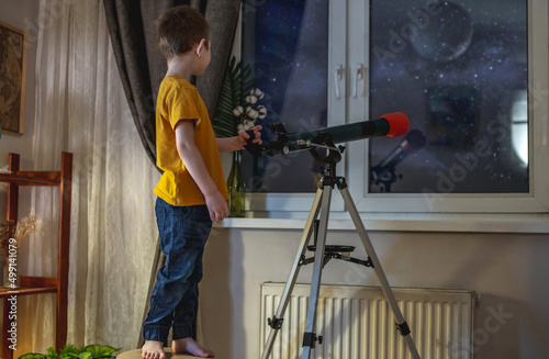 Fotobehang Cute boy is looking through a telescope at the night starry sky