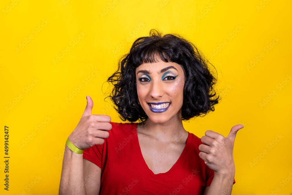 Smiling young woman in red t-shirt is showing thumbs up. Woman portrait with trendy look and bright colors on yellow background. Smiling young woman in red t-shirt is showing thumbs up. Woman portrait with trendy look and bright colors on yellow background.