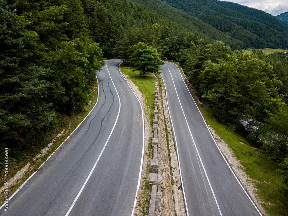 Winding road from high mountain pass, in summer time. Aerial view by drone. Romania