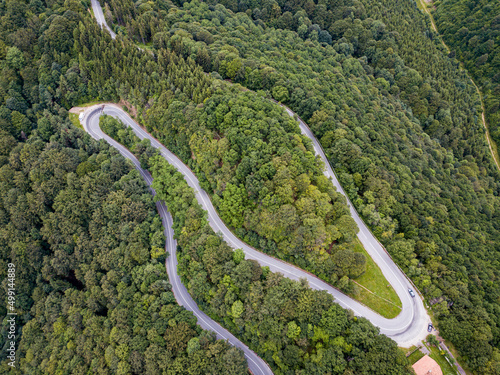 Winding road from high mountain pass, in summer time. Aerial view by drone. Romania