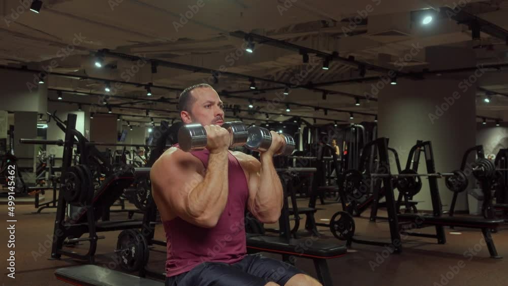 Bodybuilder raises arms with dumbbells to the sides up. Gym, sports training Bodybuilder raises arms with dumbbells to the sides up. Gym, sports training