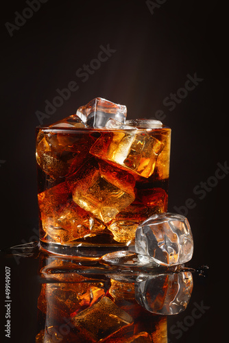 Beautiful cold drink of Cola with ice cubes. Glass of Coca Cola with ice on a black background. Shallow depth of field
