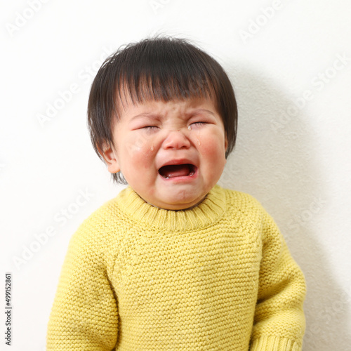 泣きそうな表情のセーターを着ている女の子の写真。