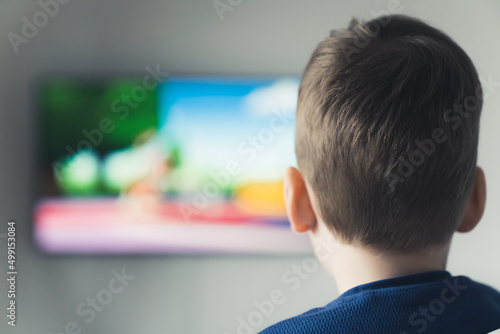 little boy watching cartoon on TV closeup shot from behind TV addiction concept indoors. High quality photo © PoppyPix