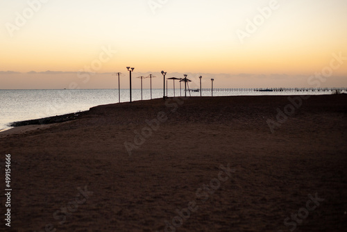 Sunrise over the red sea in egypt and abandoned sun umbrellas on the beach