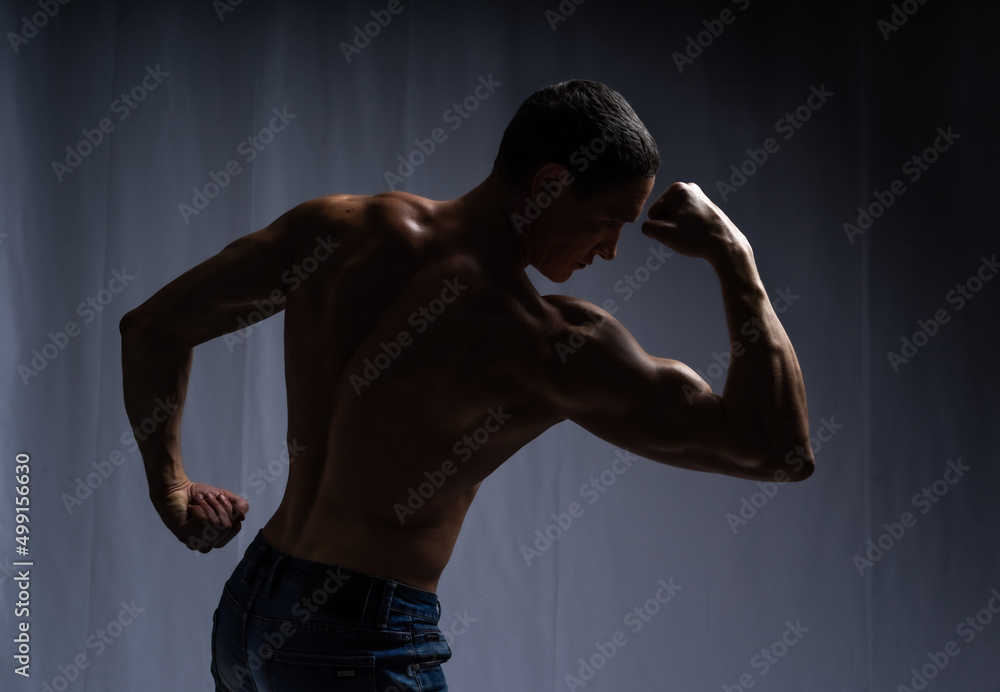 muscular silhouette black background. athletic young man. Black and white dark contrast photo of fitness muscular arms and chest. strong athletic man.