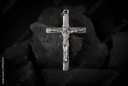 Fotografia Silver crucifix necklace cross on pieces of coal.
