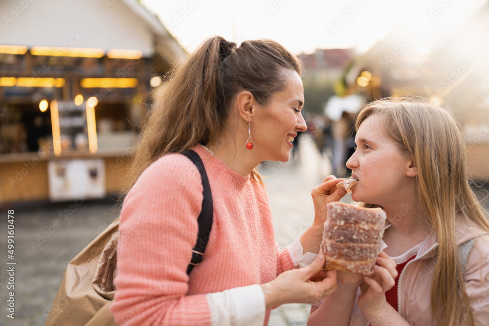 happy mother and daughter at fair in city eating trdelnik happy mother and daughter at fair in city eating trdelnik