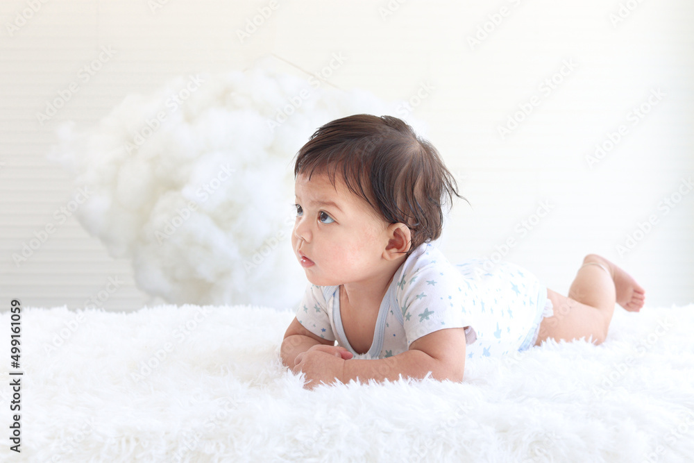 Portrait of a six months crawling baby on fluffy white rug, happy smiling adorable sweet little girl kid lying on bed in white bedroom, childhood and baby care concept Portrait of a six months crawling baby on fluffy white rug, happy smiling adorable sweet little girl kid lying on bed in white bedroom, childhood and baby care concept