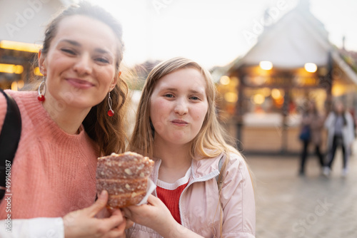happy modern mother and child at fair in city eating trdelnik