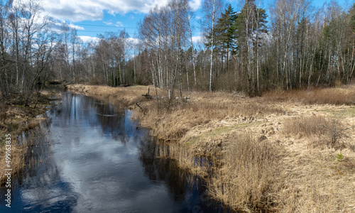 a small river in early spring, blue skies and reflections in the water